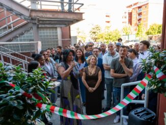 Cerimonia di inaugurazione con gruppo di persone all'aperto e nastro tricolore in primo piano.