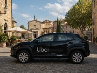 Auto nera con logo Uber parcheggiata su piazza in borgo italiano con edifici in pietra e cielo azzurro.