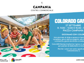 Bambini che giocano a Twister gigante in un centro commerciale durante un evento inclusivo sul daltonismo.