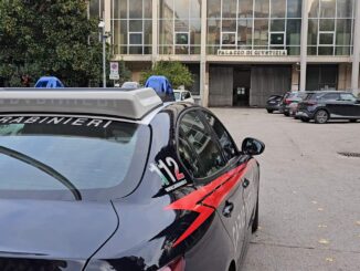Auto dei Carabinieri parcheggiata davanti a un edificio giudiziario.